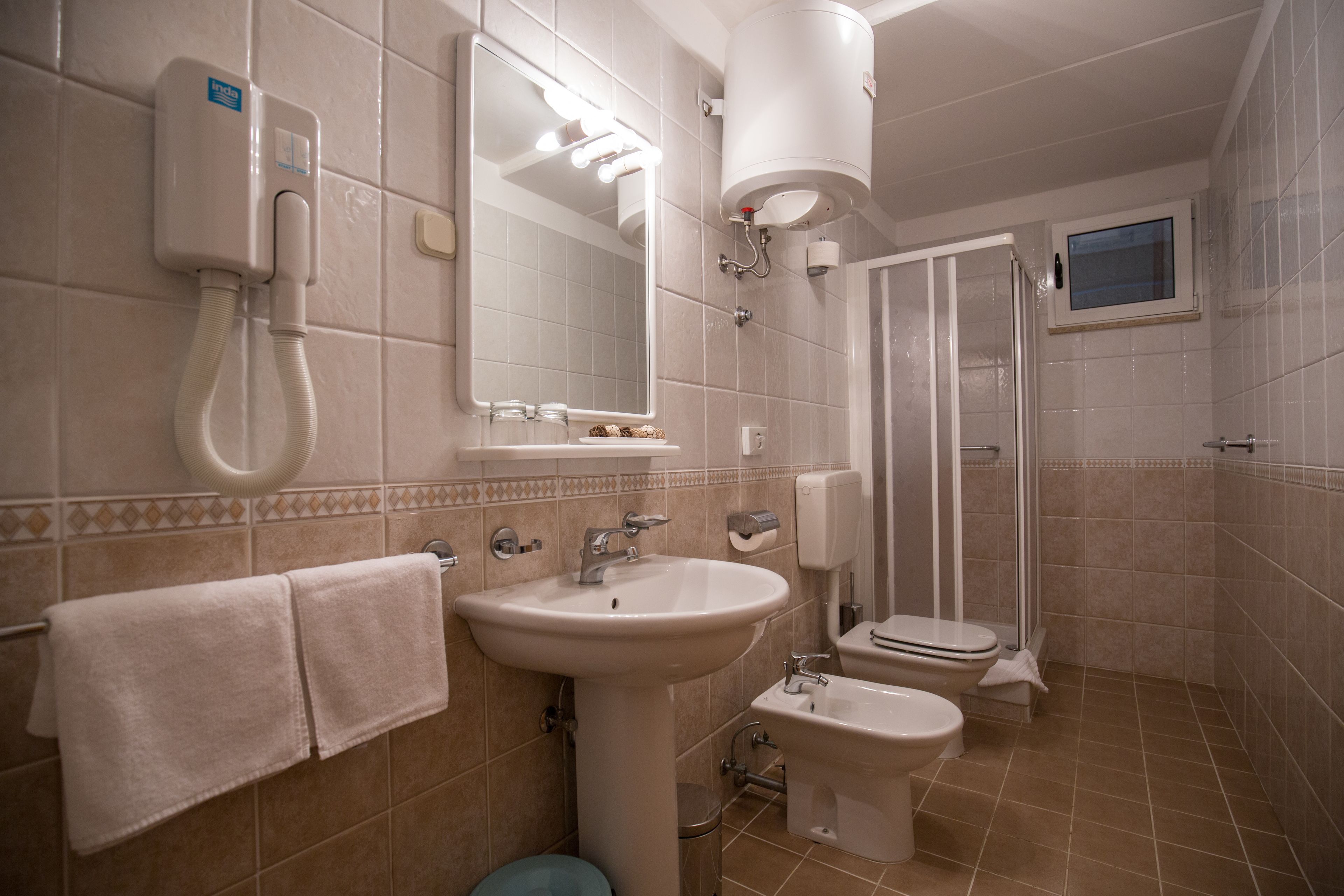 Un baño con lavamanos, inodoro, bidé y cabina de ducha.