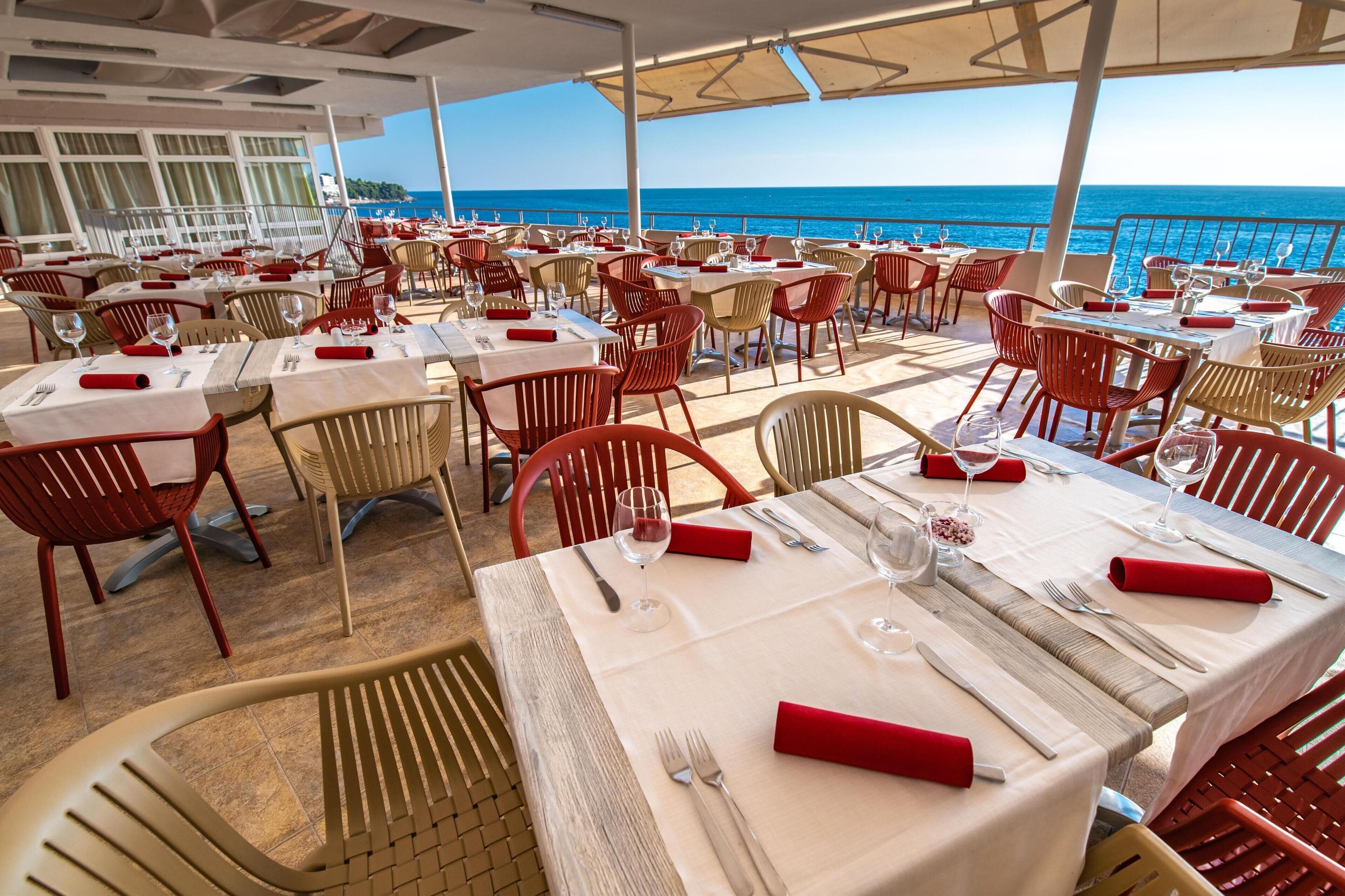 Un restaurant dont les tables sont dressées pour le service, avec vue sur un plan d’eau.