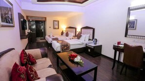 Una habitación de hotel con una cama, dos mesitas de noche, una mesa de centro, un sofá y un escritorio con una silla.