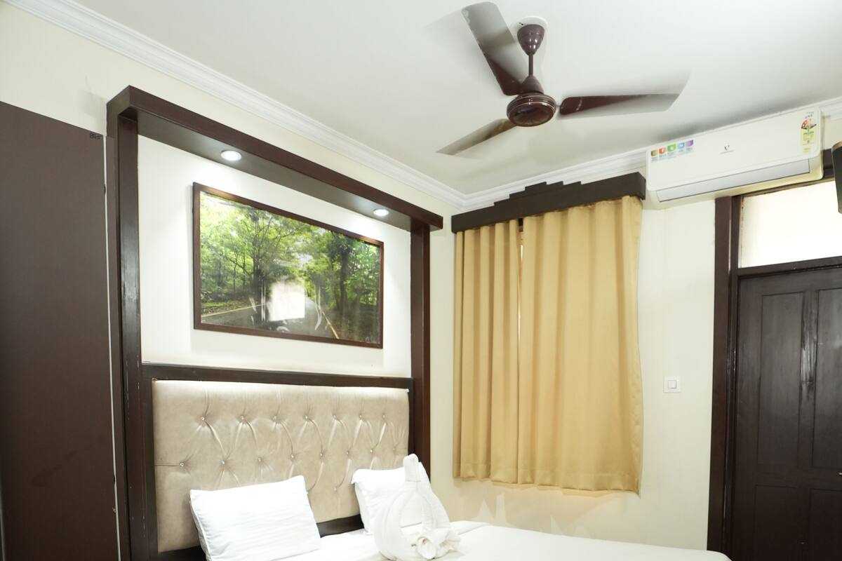 A neatly arranged bedroom with a bed, a ceiling fan, and a window with curtains.