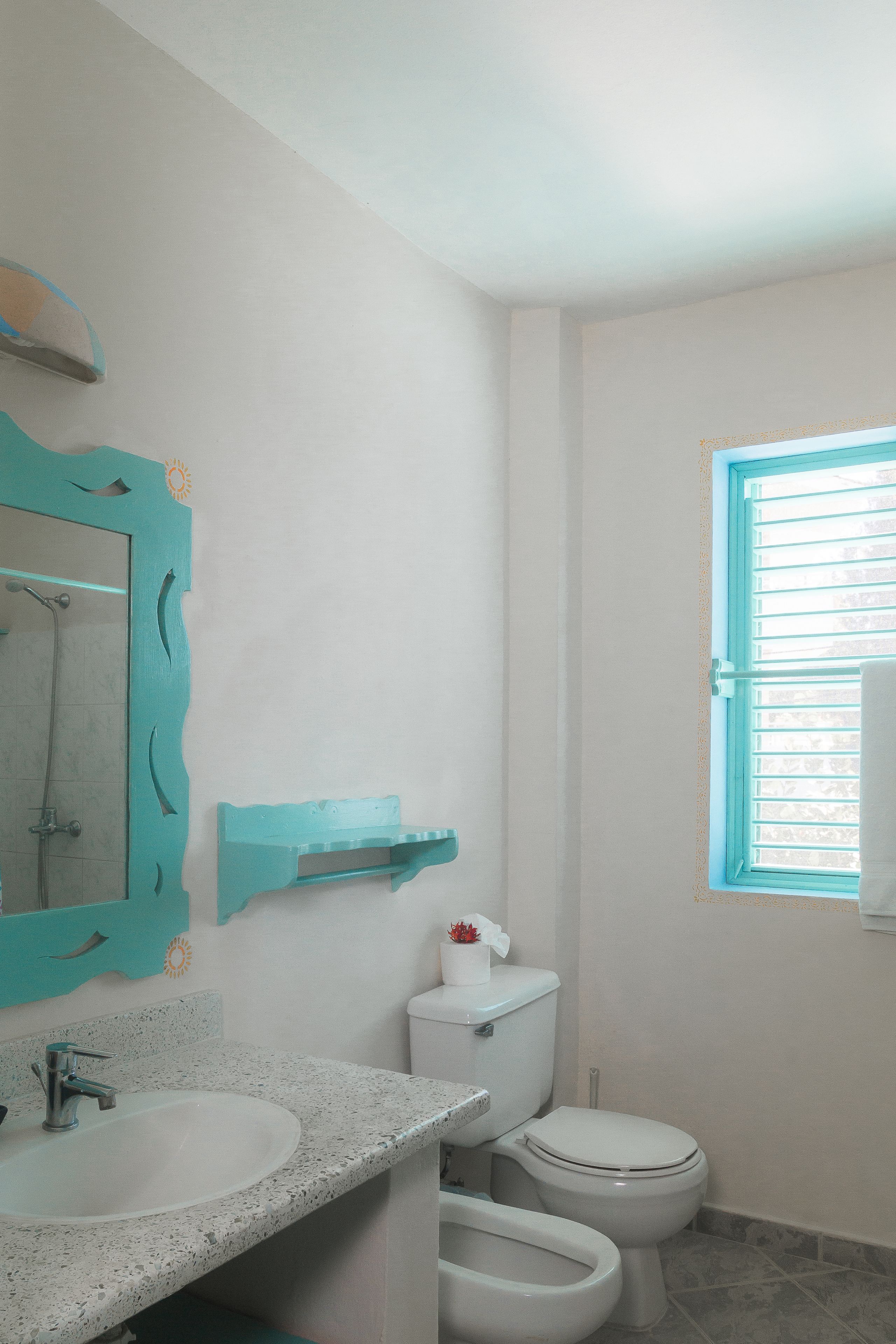 A bathroom with a white sink, a toilet, and a window with blinds.