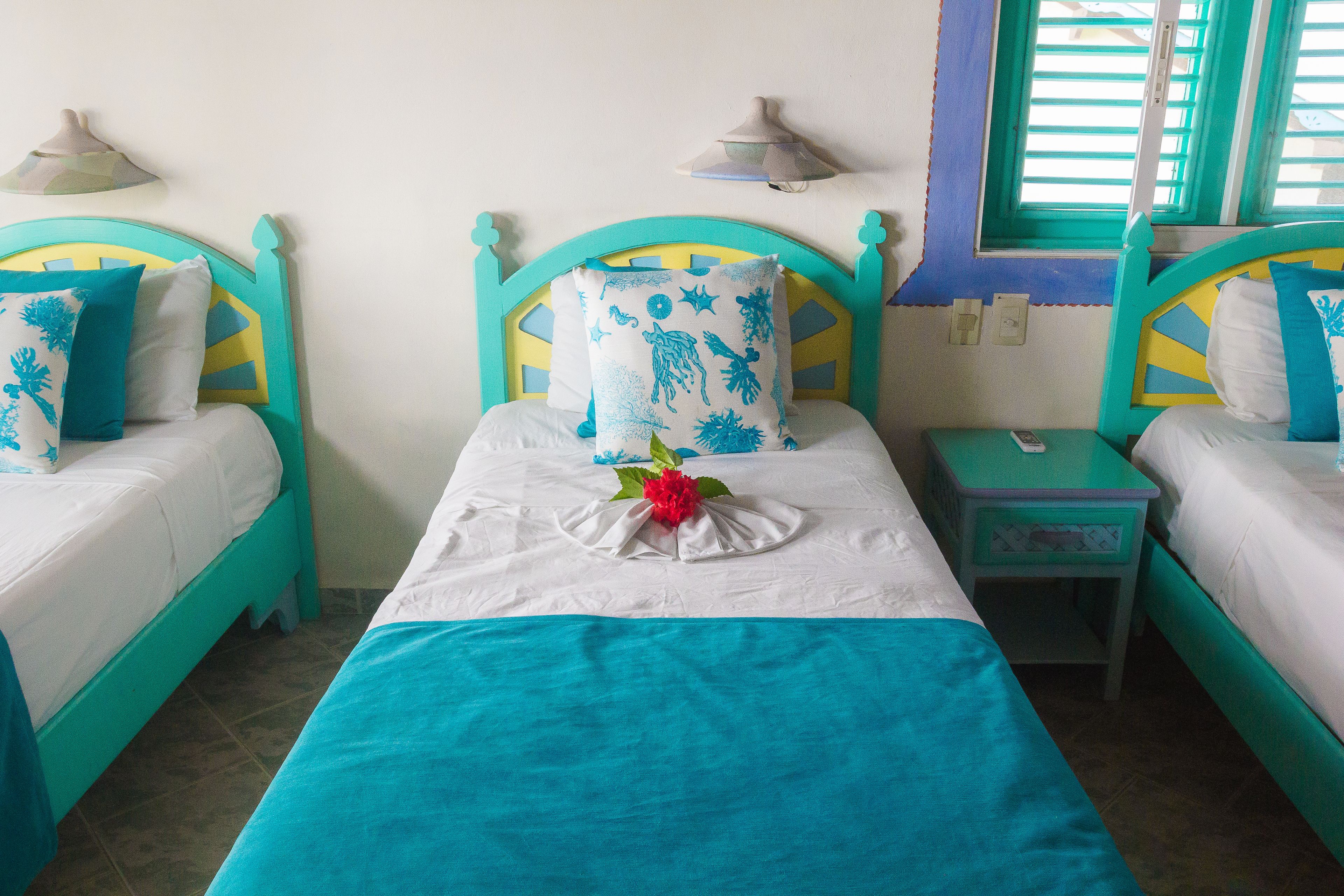 Une chambre avec deux lits, chacun doté d’une tête de lit bleue et blanche, et une petite table de chevet avec une lampe.