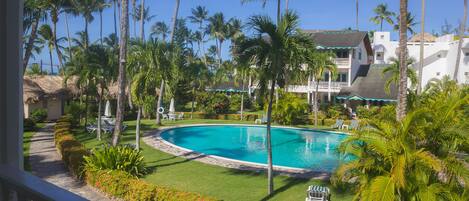 A pool surrounded by palm trees and a well-maintained lawn.