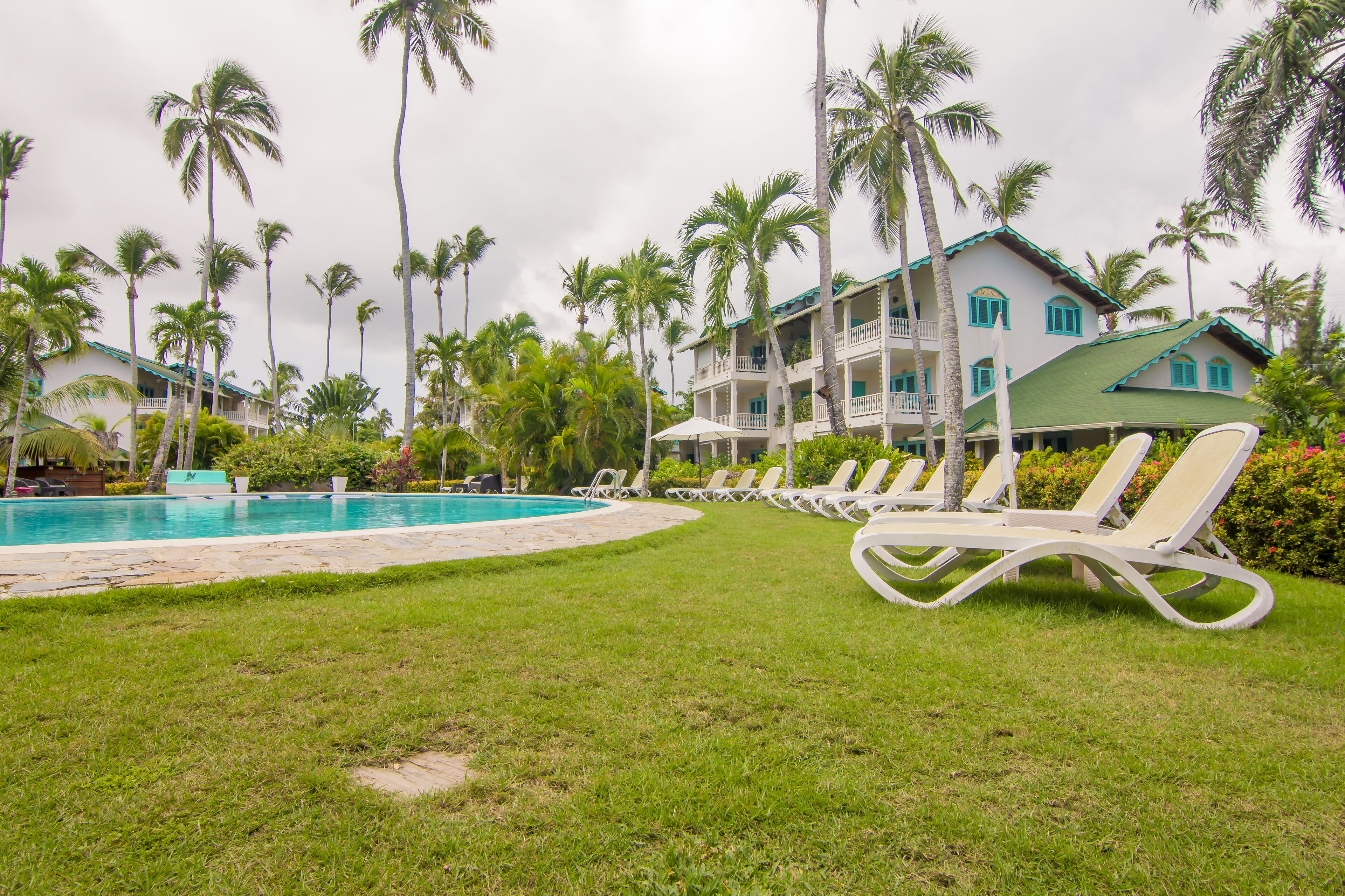 Un resort con piscina, sillas de descanso y palmeras.