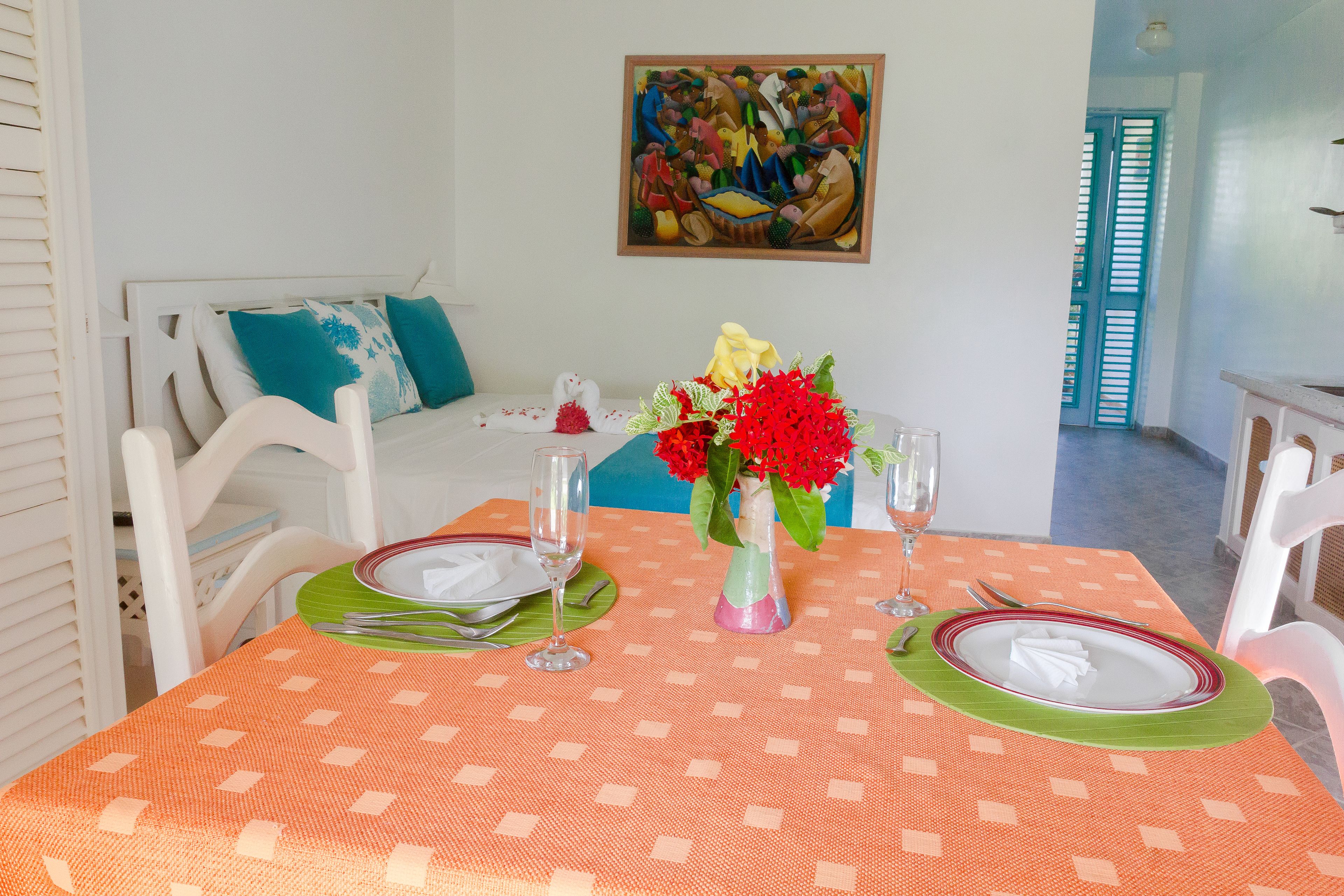 A dining table set with plates, cutlery, and a vase of flowers.