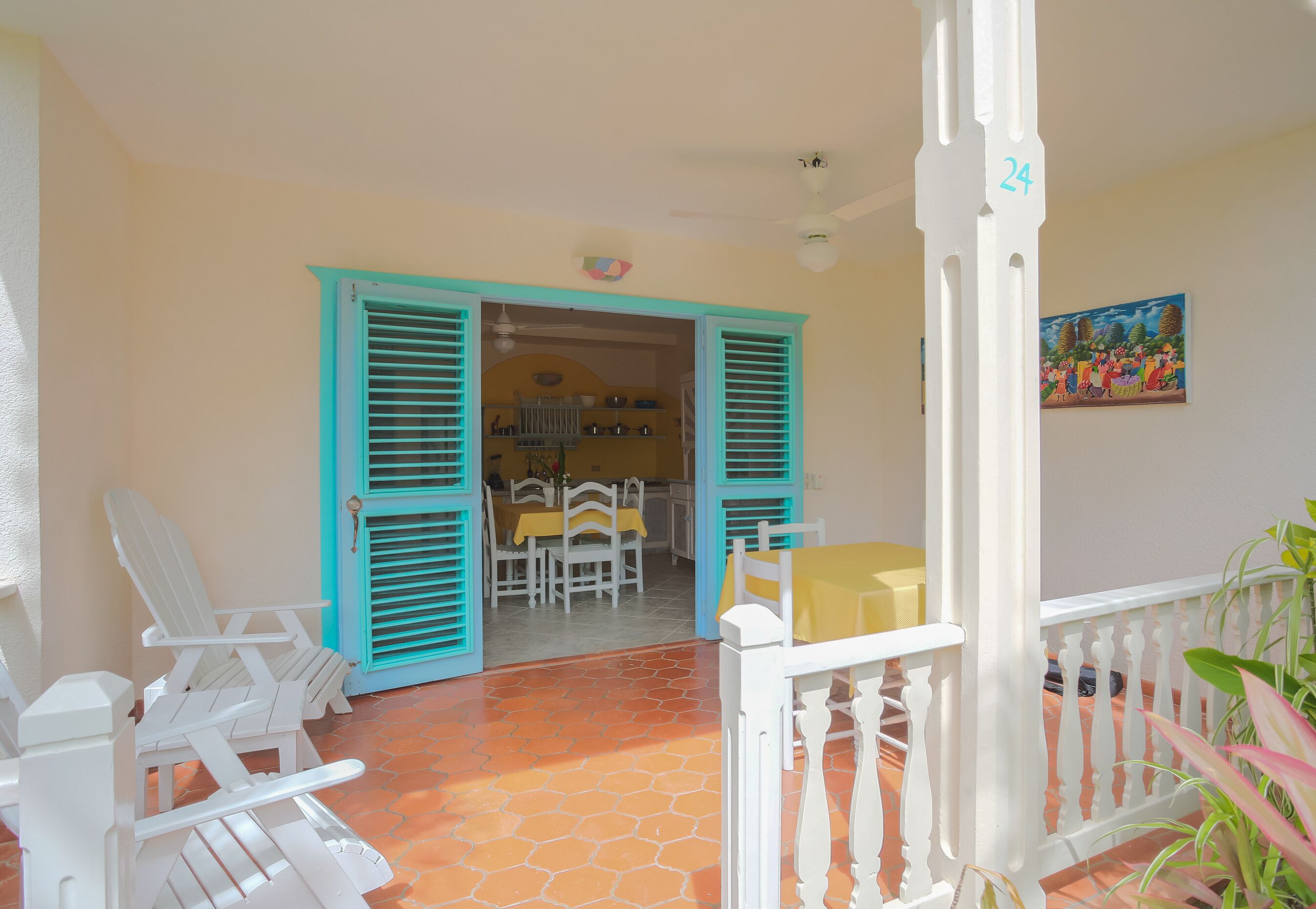 A patio area with white chairs, a table, and a door with turquoise shutters.