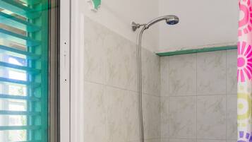 A shower with a handheld showerhead, a wall-mounted faucet, and a colorful shower curtain.