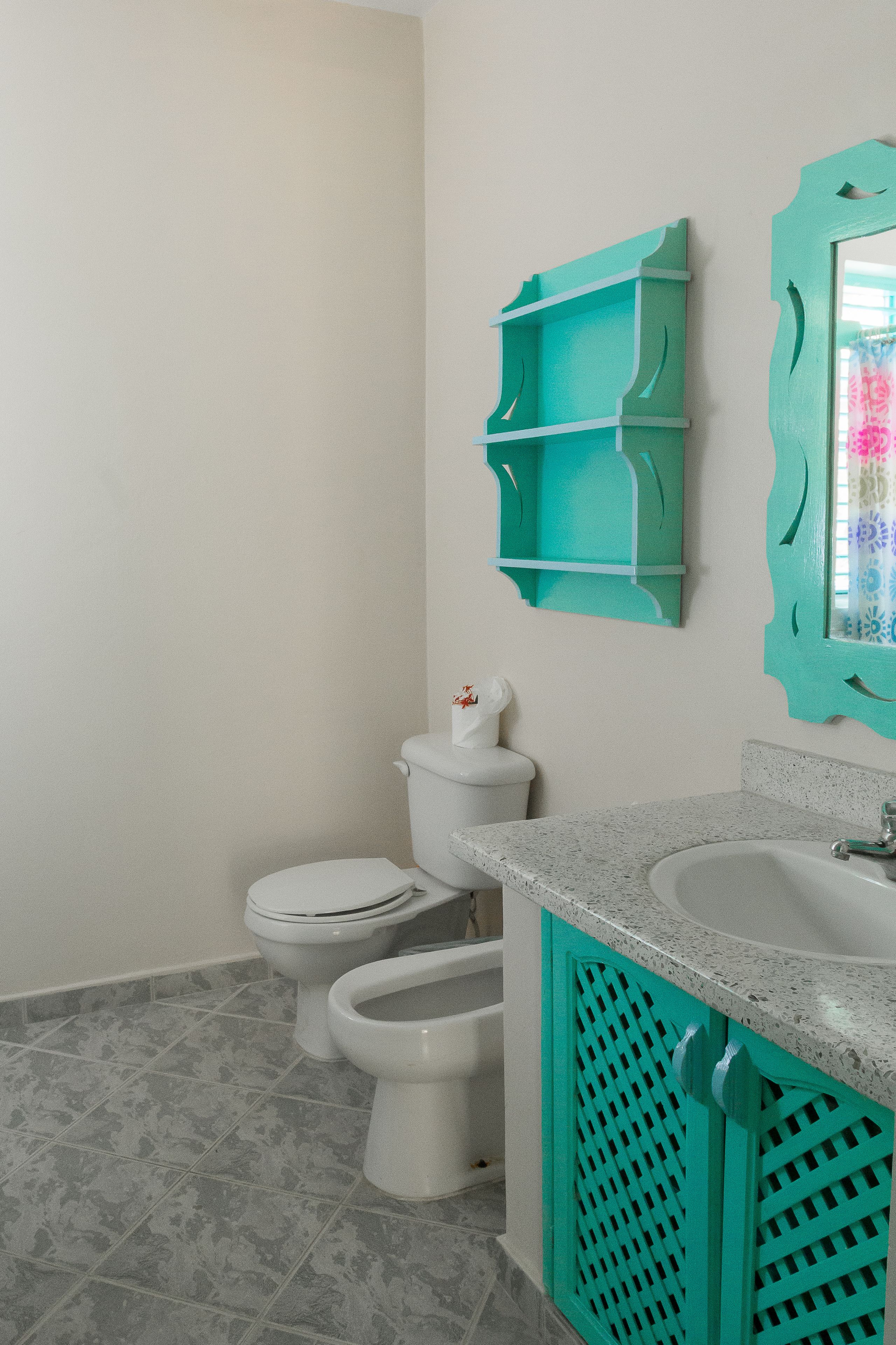 A bathroom with two toilets, a sink, and a mirror.