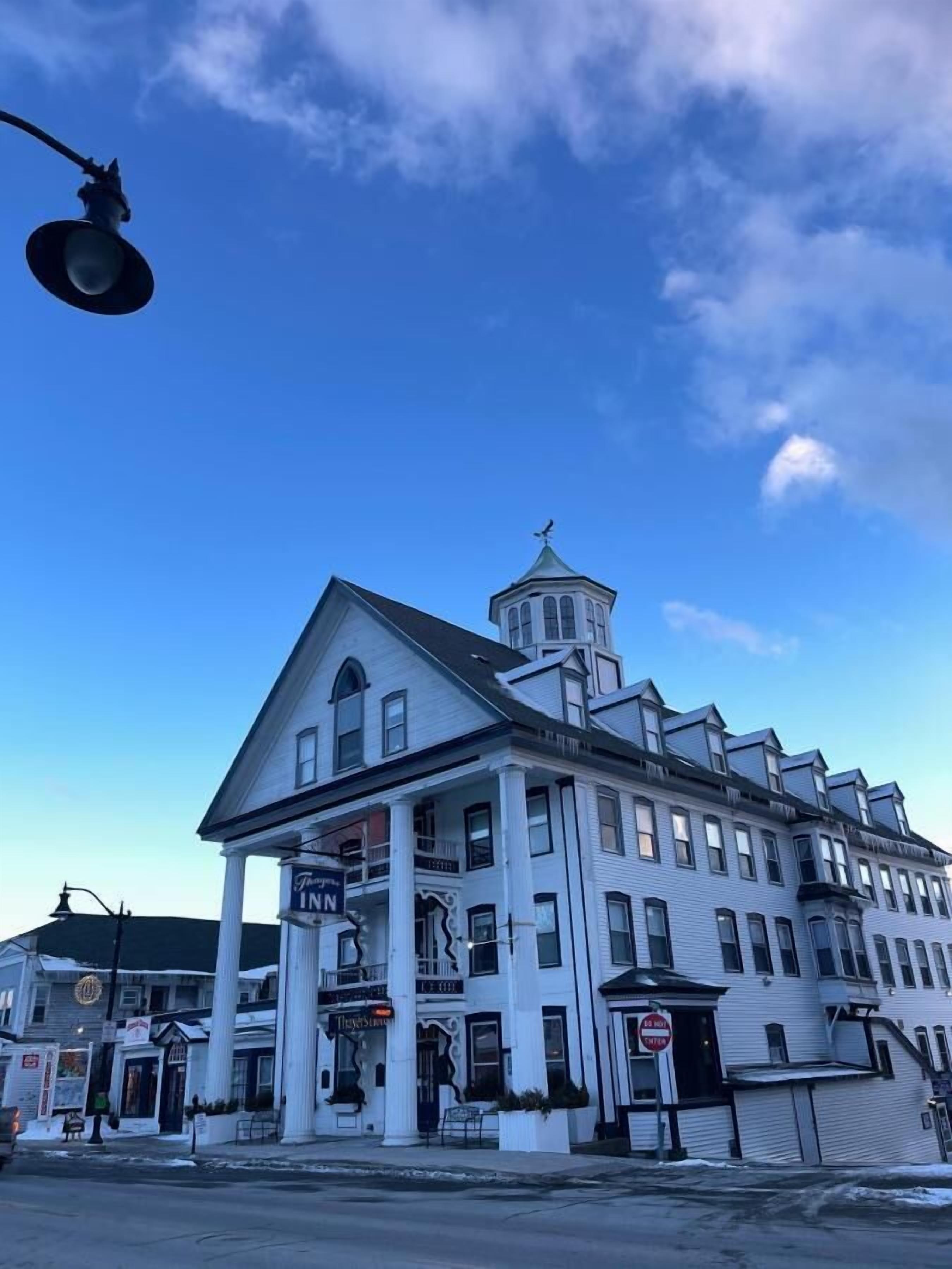Un edificio histórico con una torre destacada, múltiples ventanas y un letrero que dice 'The Inn'.
