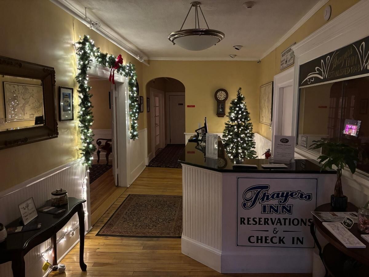 A hotel reception area with a check-in counter, Christmas decorations, and a clock on the wall.