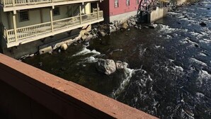 Un río con una rueda hidráulica y edificios a lo largo de la orilla.
