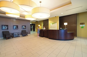 A hotel reception area with a check-in counter, seating area, and a wall with a patterned design.