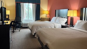 A hotel room with two beds, a desk with a computer, a chair, and a TV.