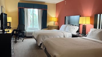 Una habitación de hotel con dos camas, un escritorio con ordenador, una silla y un televisor.