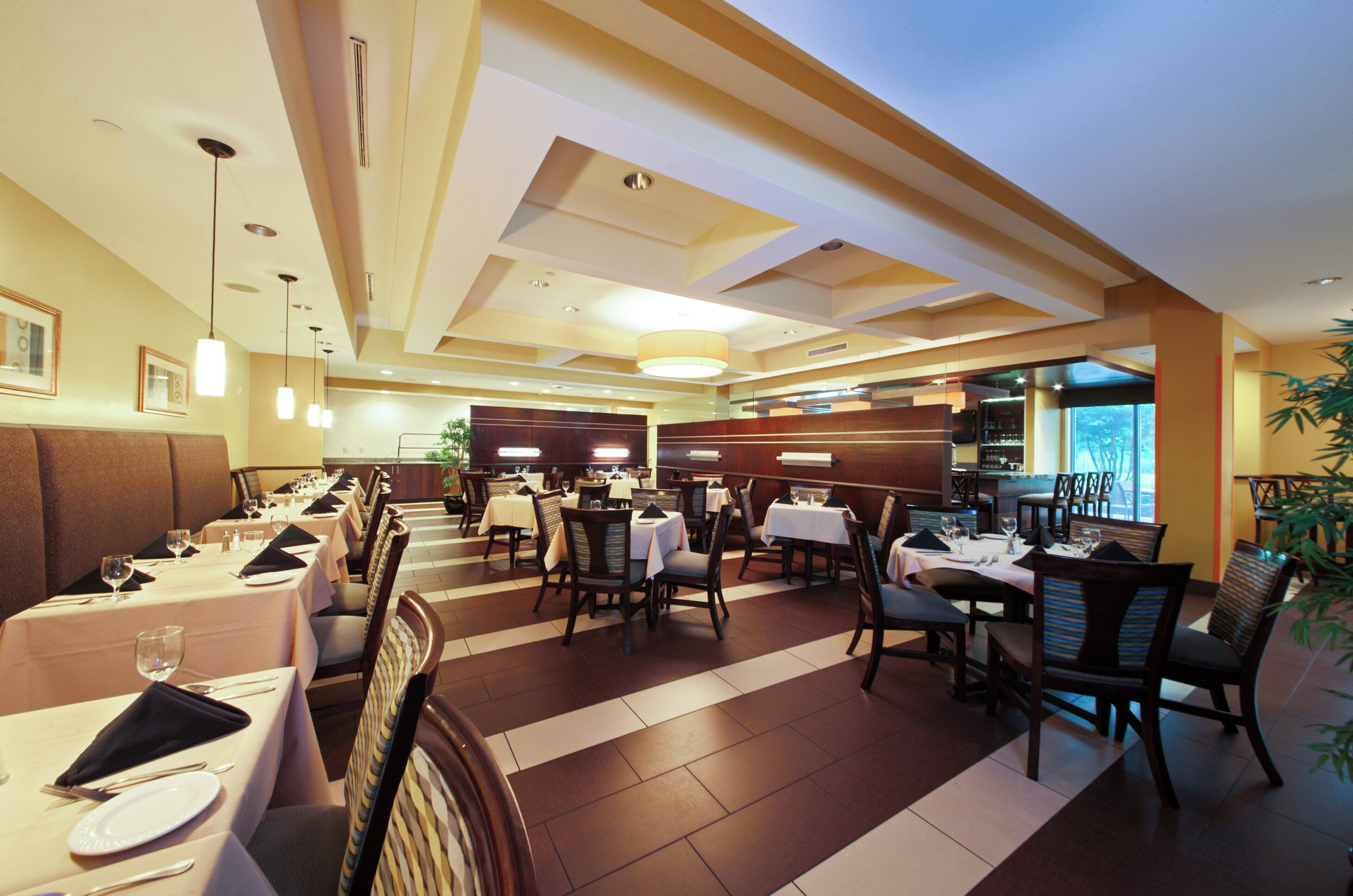 A restaurant with multiple dining tables and chairs, a bar area, and a view of the outdoors.