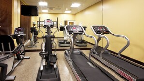 Un gimnasio con cintas de correr, elípticas y una bicicleta estática.