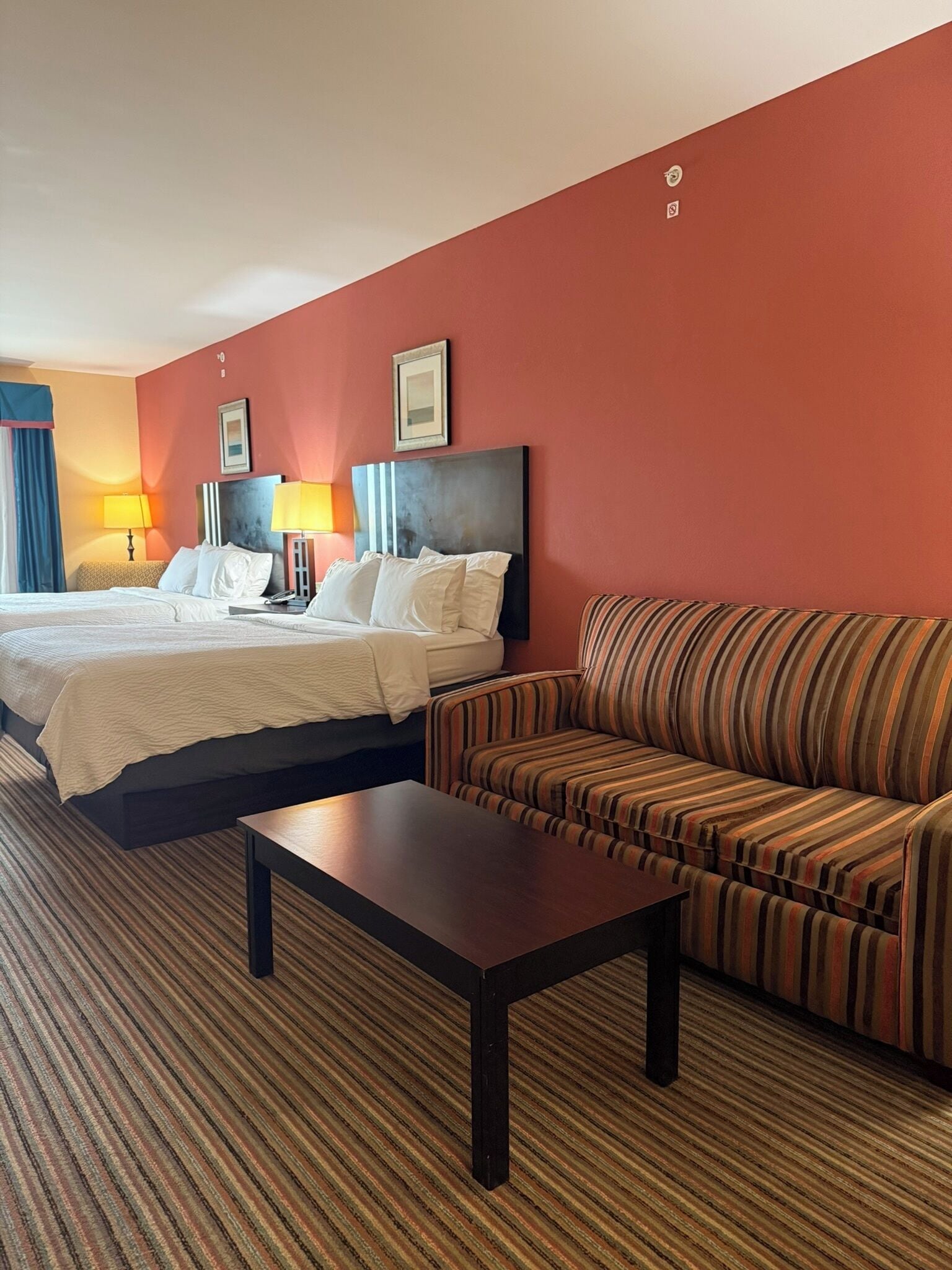 A hotel room with a bed, a sofa, a coffee table, and a lamp.