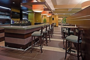 A bar area with a counter, stools, and a seating area with tables and chairs.
