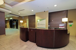 A reception desk with a glass top and a wooden base, a wall-mounted sign, and a floor with a patterned design.