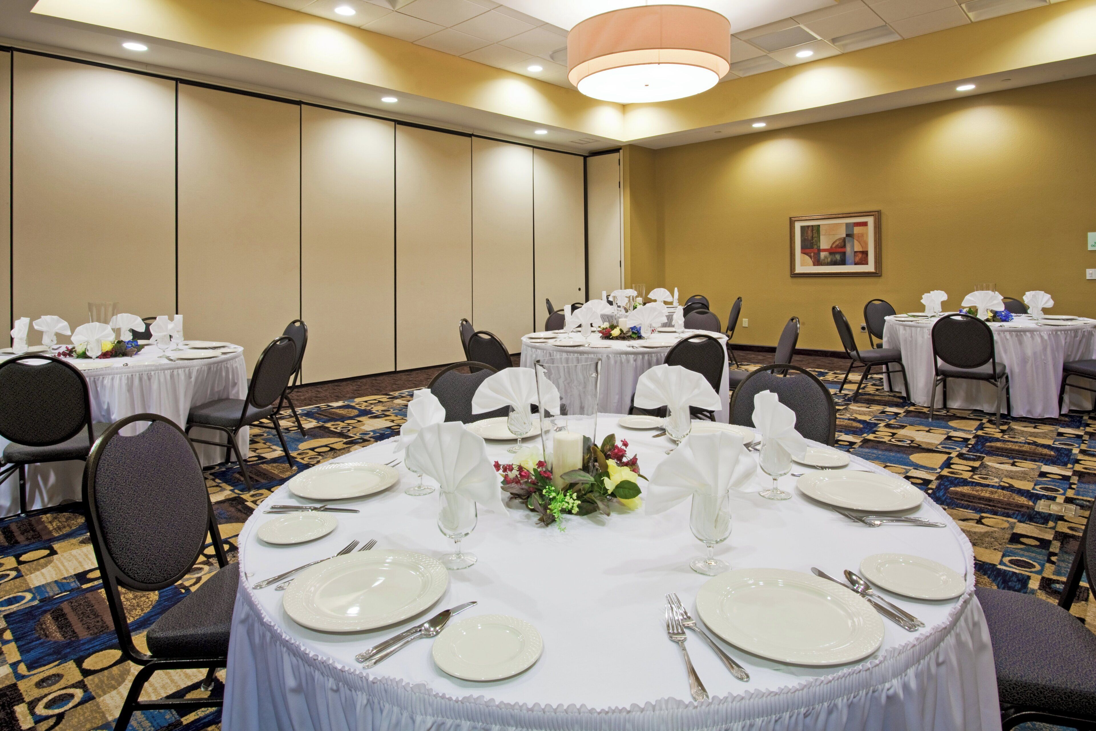 A conference room with round tables, chairs, and a carpeted floor.