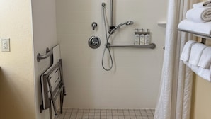 A small, tiled shower area with a grab bar, a towel rack, and a showerhead.