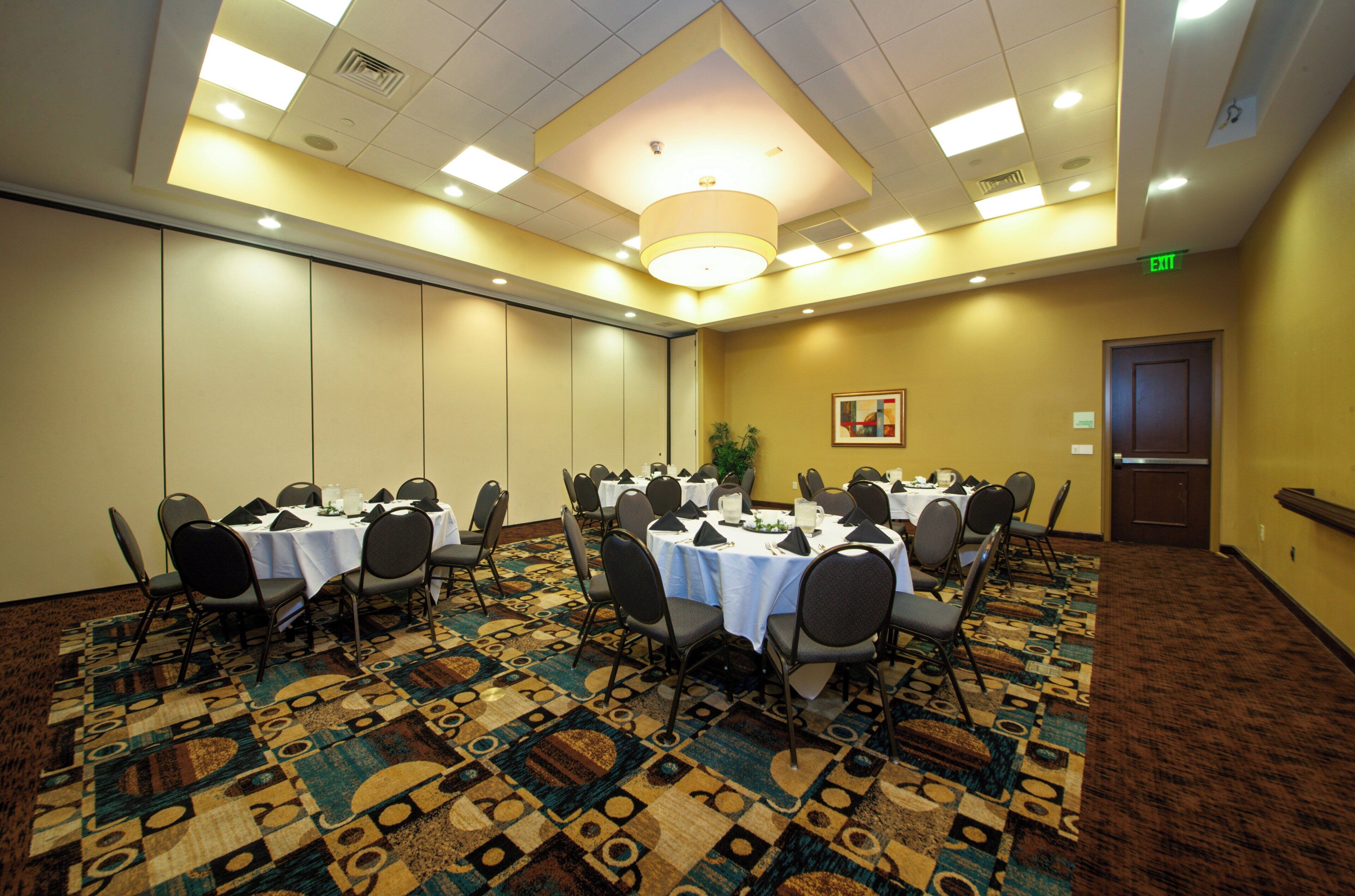 A conference room with tables set for a meeting, equipped with chairs and a patterned carpet.