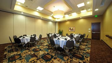 A conference room with tables set for a meeting, equipped with chairs and a patterned carpet.