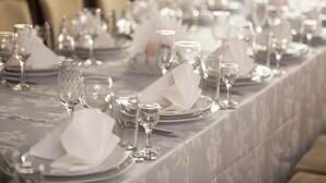A long dining table set with multiple plates, glasses, and cutlery, covered with a floral tablecloth. - Jumbo Hotel (Chisinau)