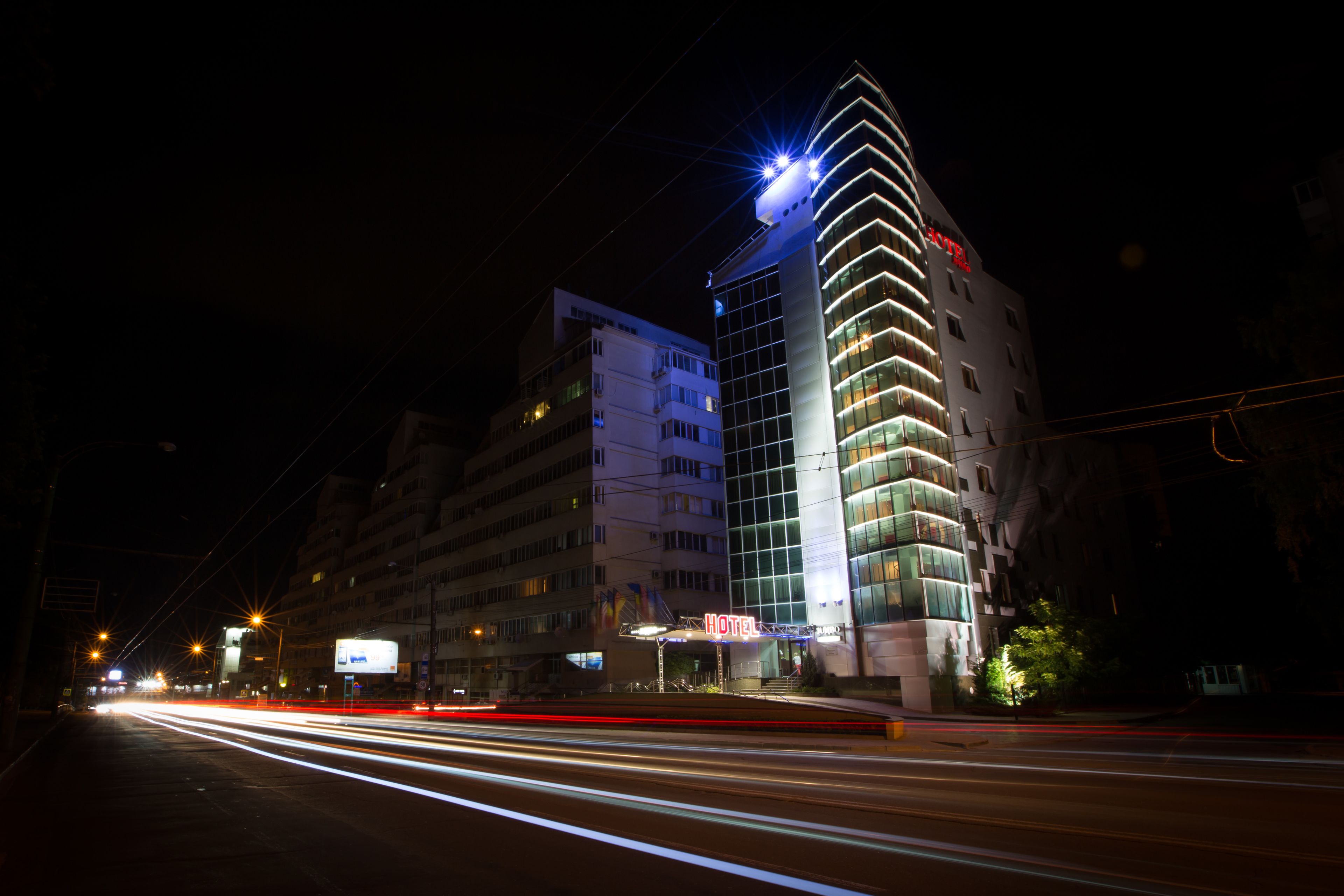 Un hotel dal design moderno, con una facciata curva ben evidente e insegne illuminate.