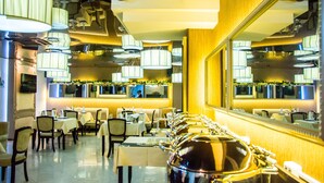 A restaurant with multiple tables, chairs, and a buffet line with covered dishes. - Jumbo Hotel (Chisinau)
