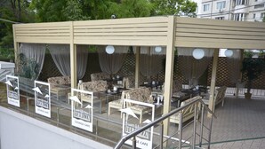 An outdoor lounge area with tables and chairs, covered by a canopy, and signs indicating it is a lounge cafe. - Jumbo Hotel (Chisinau)