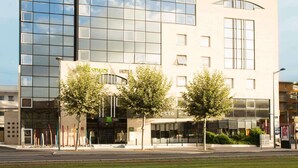 A modern building with a glass facade, a ground-level entrance, and a sign for 'Ibis'. - ibis Styles Bordeaux Meriadeck (Bordeaux)