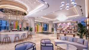 Un hall d’hôtel moderne comprenant un bar, des espaces de détente et un comptoir d’accueil.