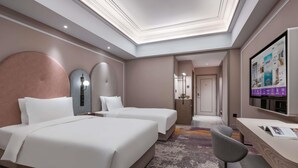 Une chambre d’hôtel avec deux lits, un bureau, une chaise, une télévision et une salle de bain visible à travers une porte ouverte.