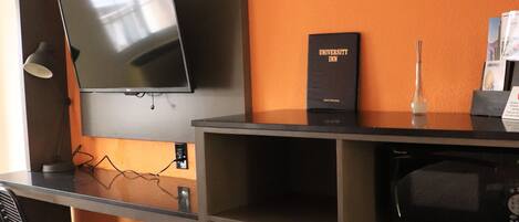 A hotel room with a desk, a flat-screen TV, a minibar, and a refrigerator.