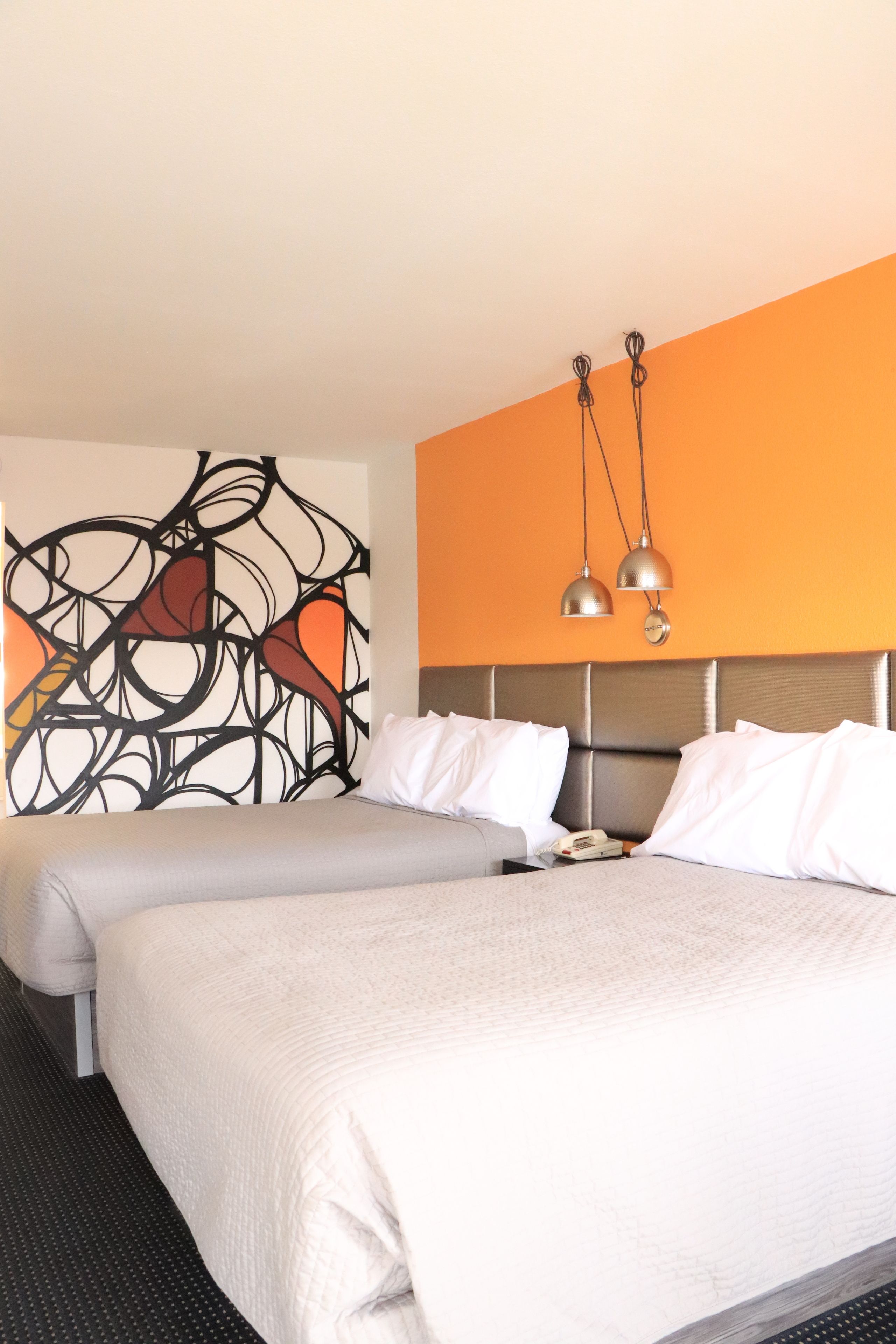 Una habitación de hotel con una cama grande, cabecera y una obra de arte en la pared.