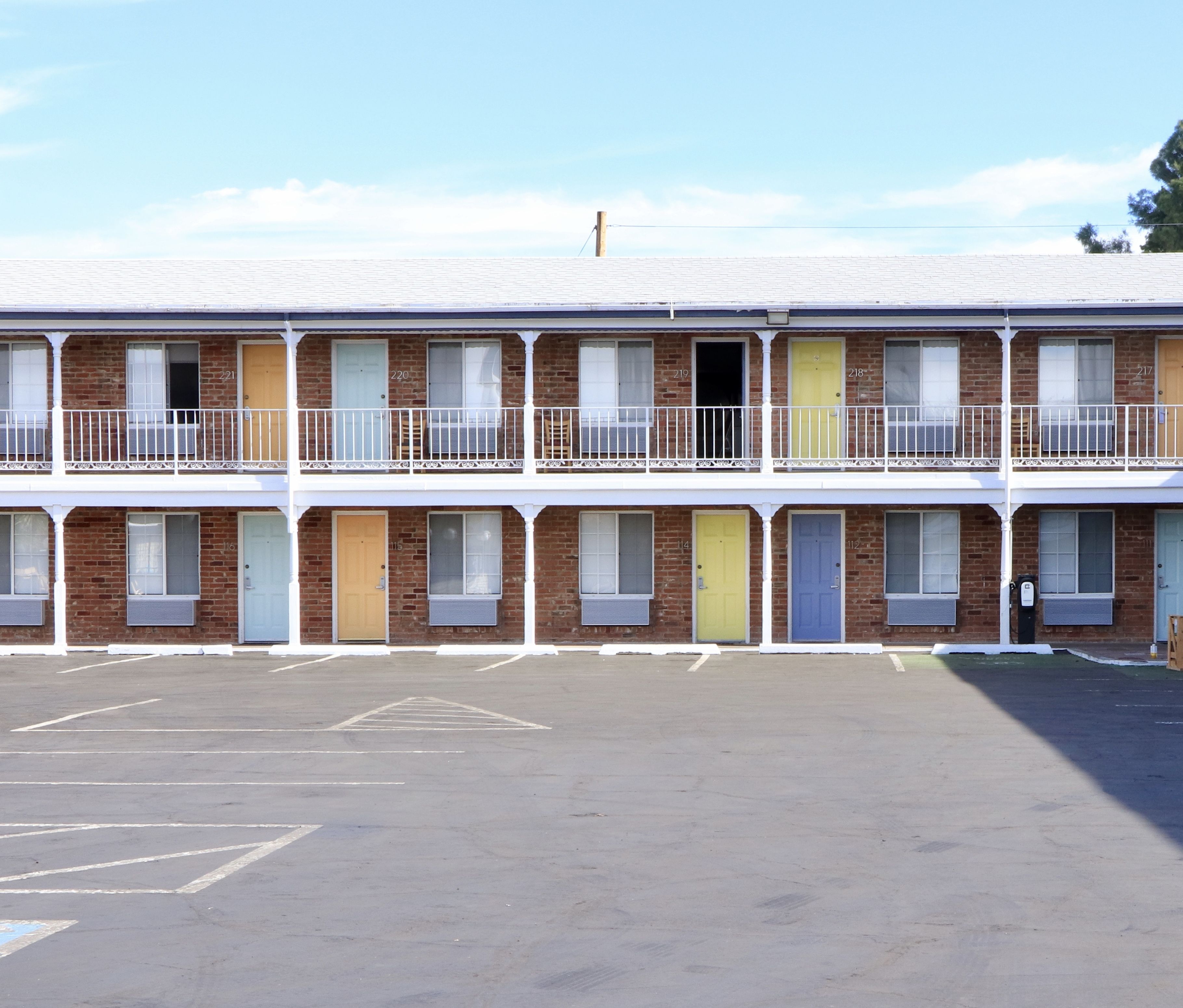 A two-story motel with a parking lot in front.