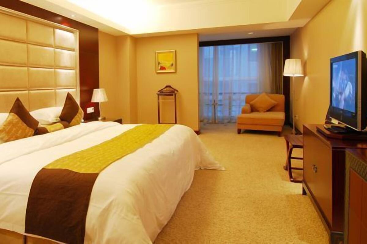 A hotel room with a large bed, a television, a desk, and a chair.