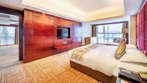Ein Hotelzimmer mit einem großen Bett, einem an der Wand montierten Fernseher und einem Fenster mit Stadtblick.