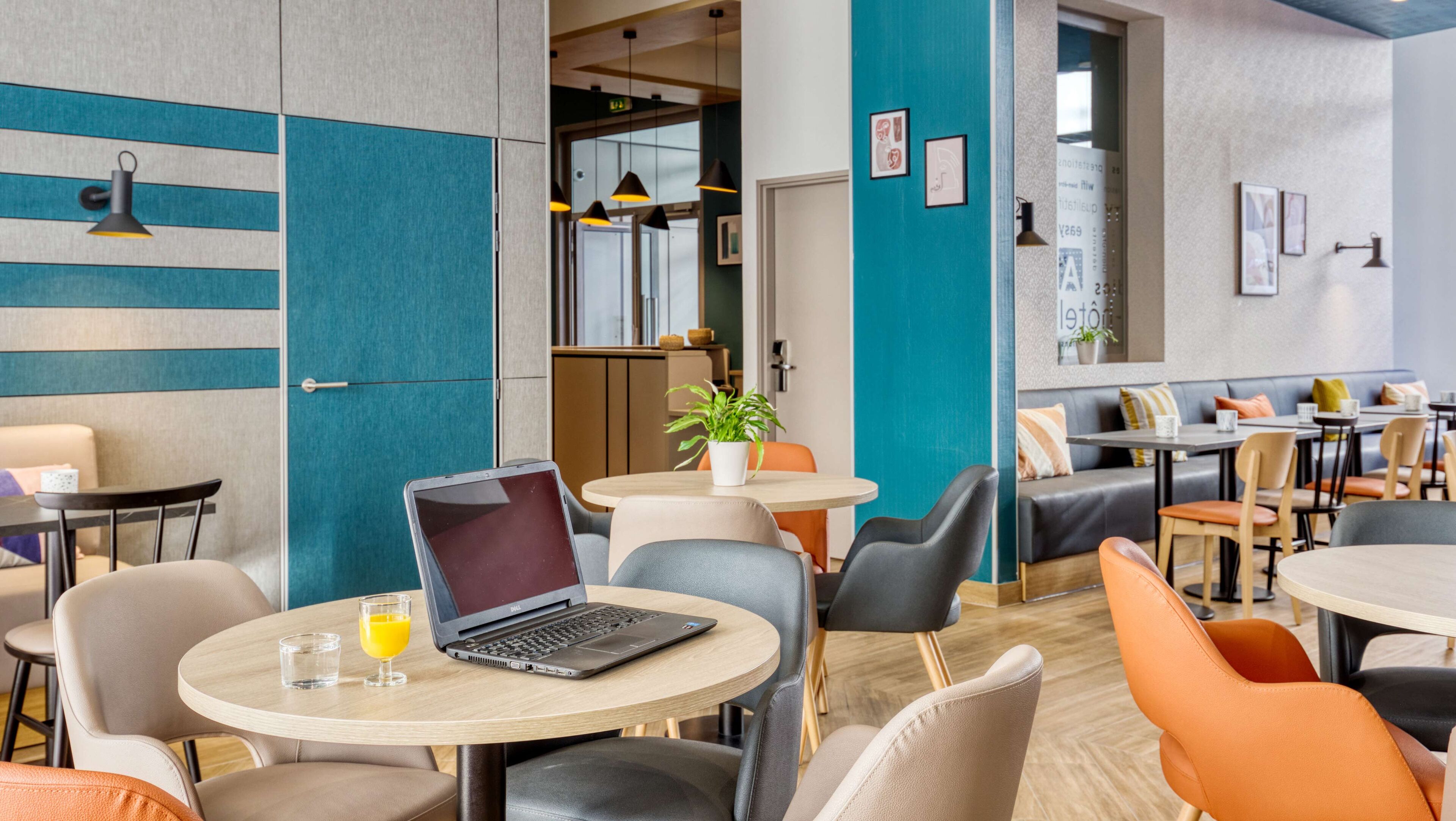 A modern dining area with round tables, chairs, and a laptop on one table.