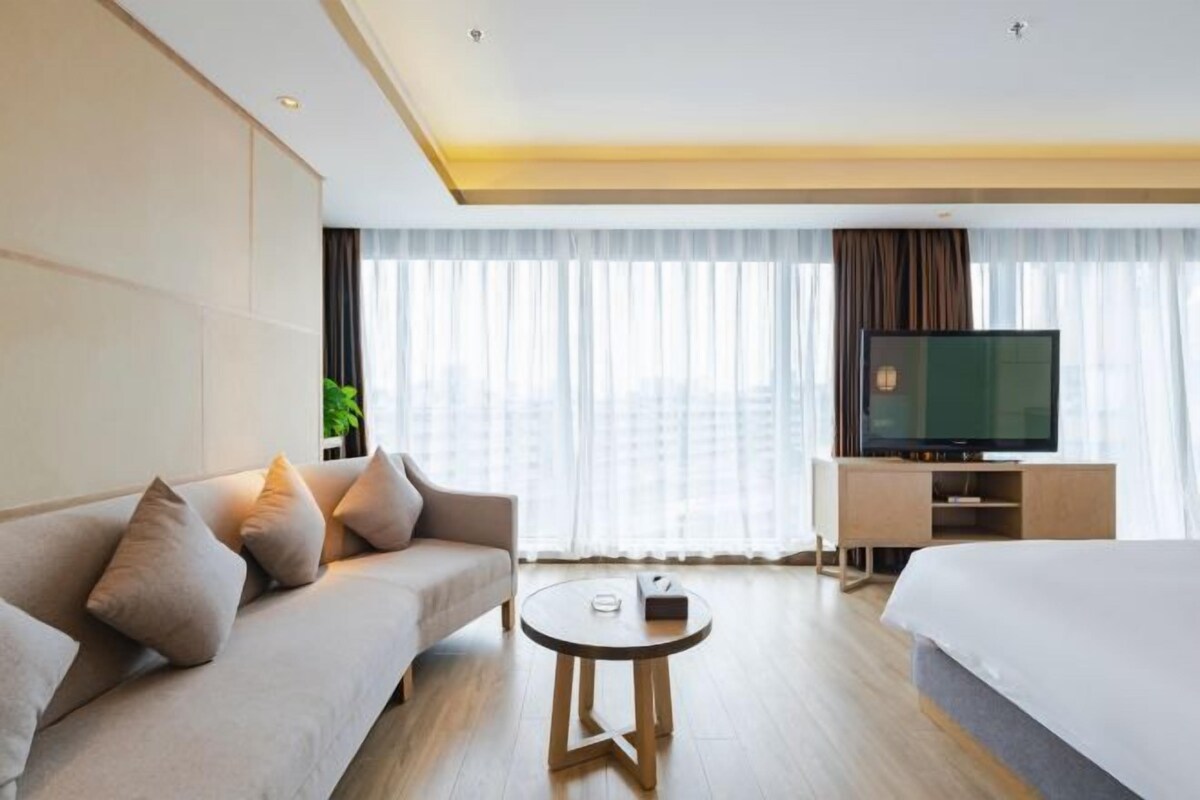 Une chambre d’hôtel moderne équipée d’un canapé, d’un lit, d’une télévision et d’une petite table.