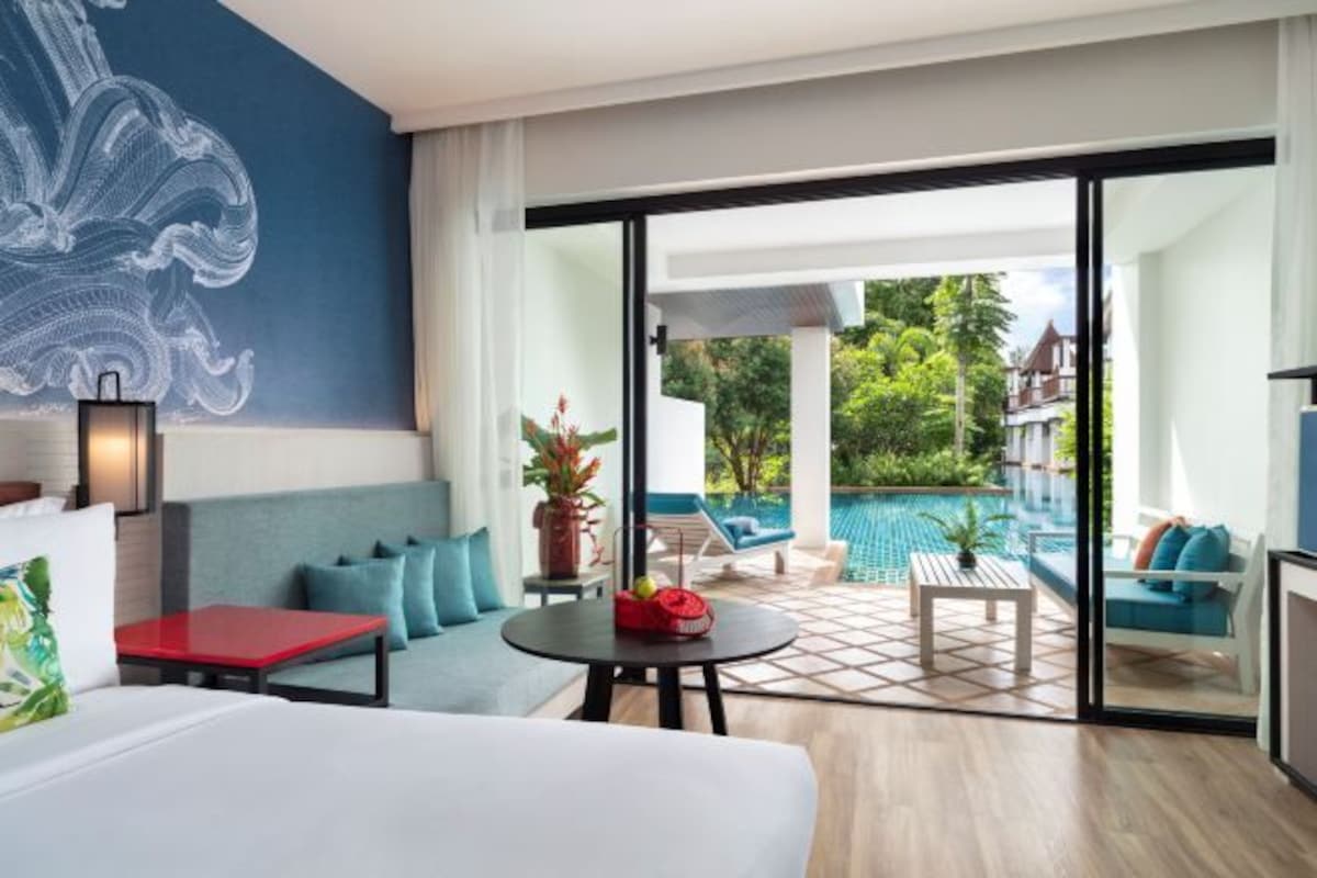 Una habitación de hotel moderna con un amplio ventanal corredero que da a una zona de piscina.