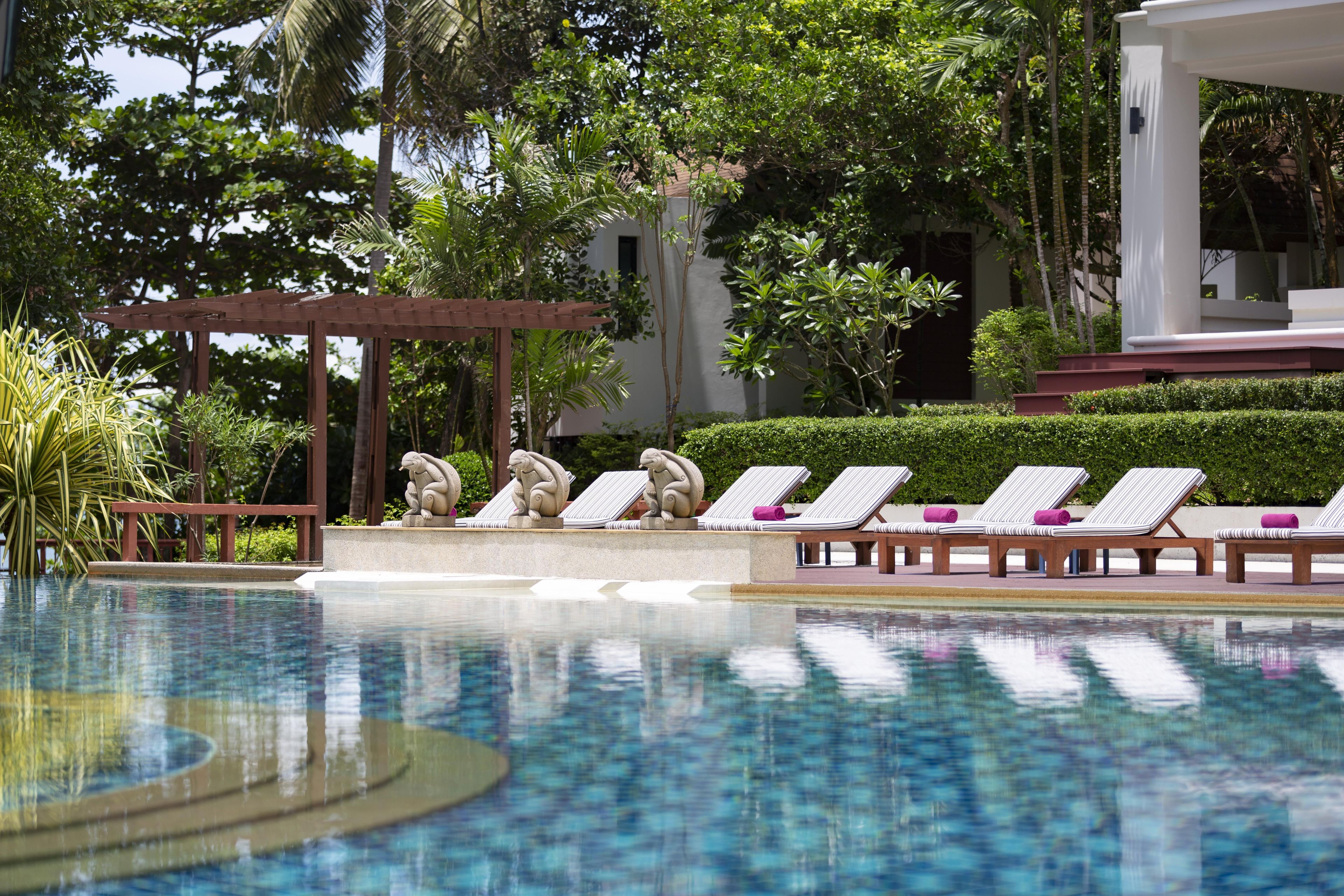 A pool area with lounge chairs and a pergola.
