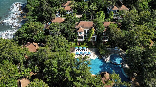 Vista aérea de un resort con varias edificaciones, una piscina grande y una zona de playa.