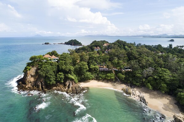 A coastal property with a beach, ocean, and forested area.