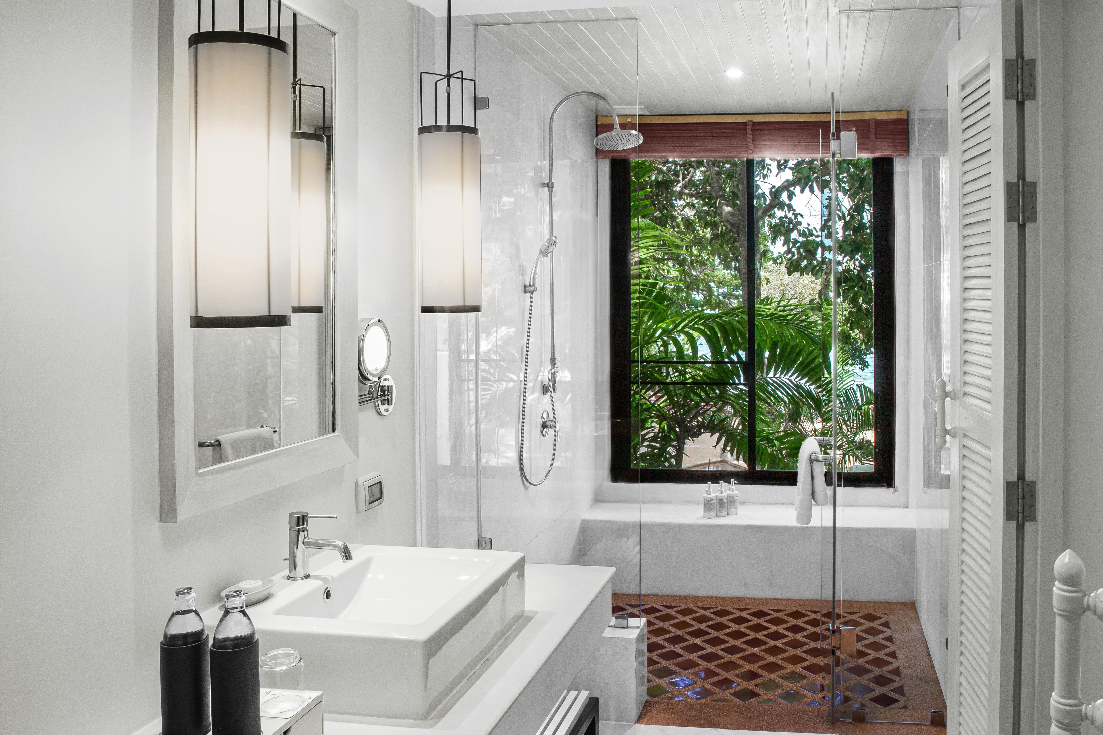 A modern bathroom with a large window, a walk-in shower, and a white sink.