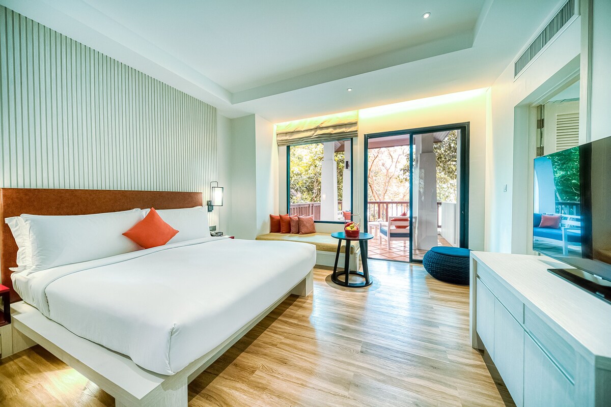 Een moderne hotelkamer met een groot bed, een televisie en een balkon met uitzicht.