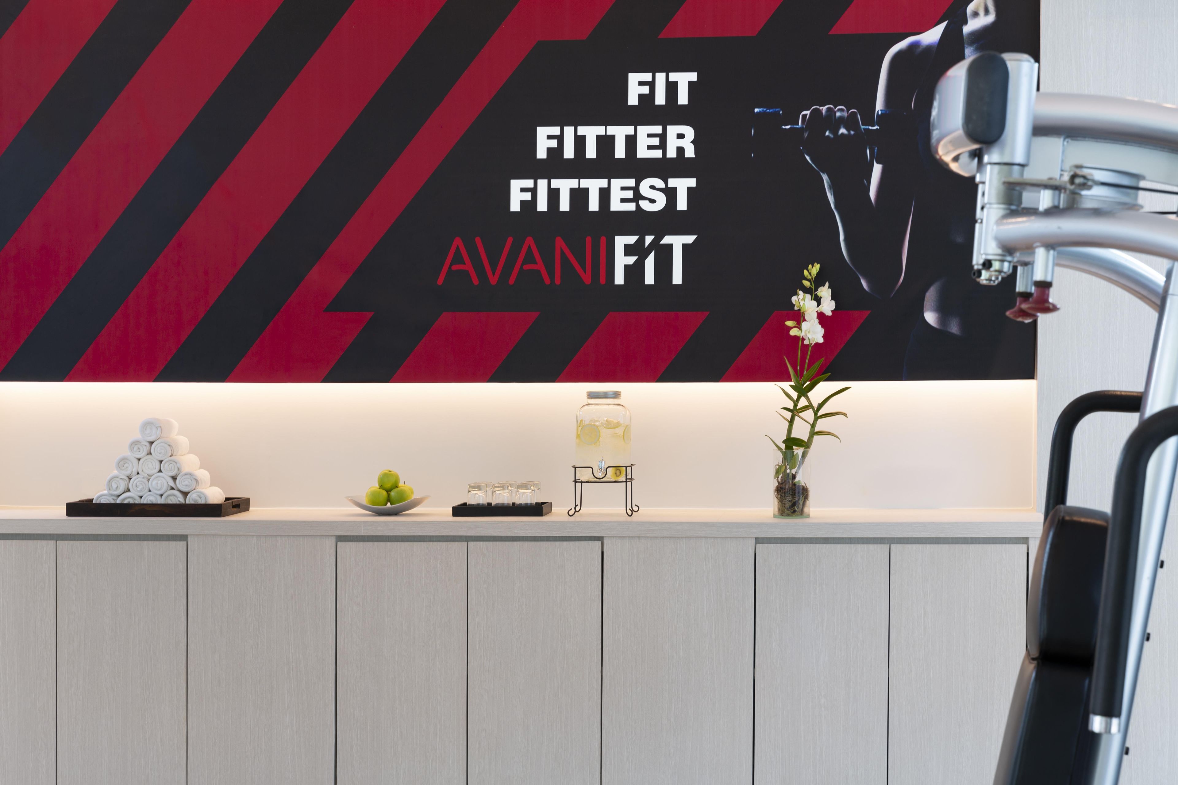 A reception desk with a modern design, featuring a logo and text on the wall, a water dispenser, and a small plant.
