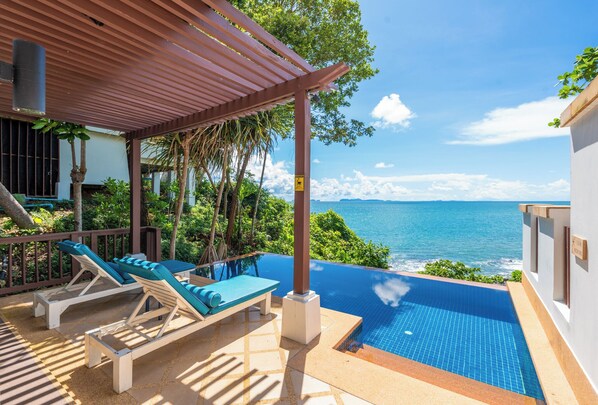 Un espace aménagé au bord de la piscine, avec des chaises longues et une vue sur l’océan.