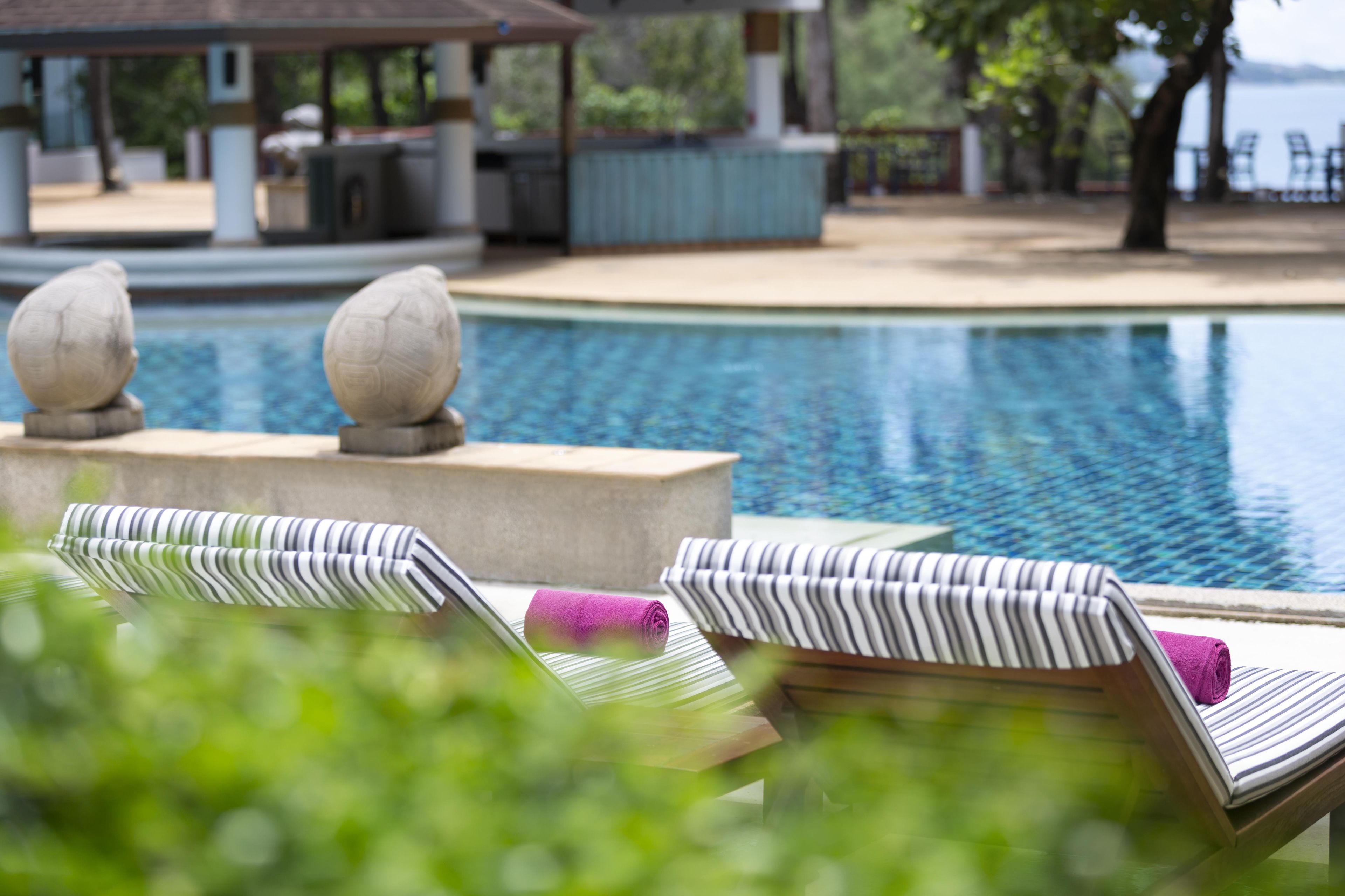 A poolside area with lounge chairs and a stone balustrade.